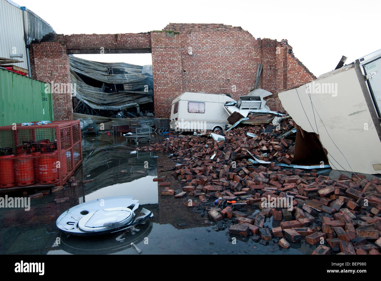 Crushed Caravan and collapsed brick wall following fire and high winds Stock Photo