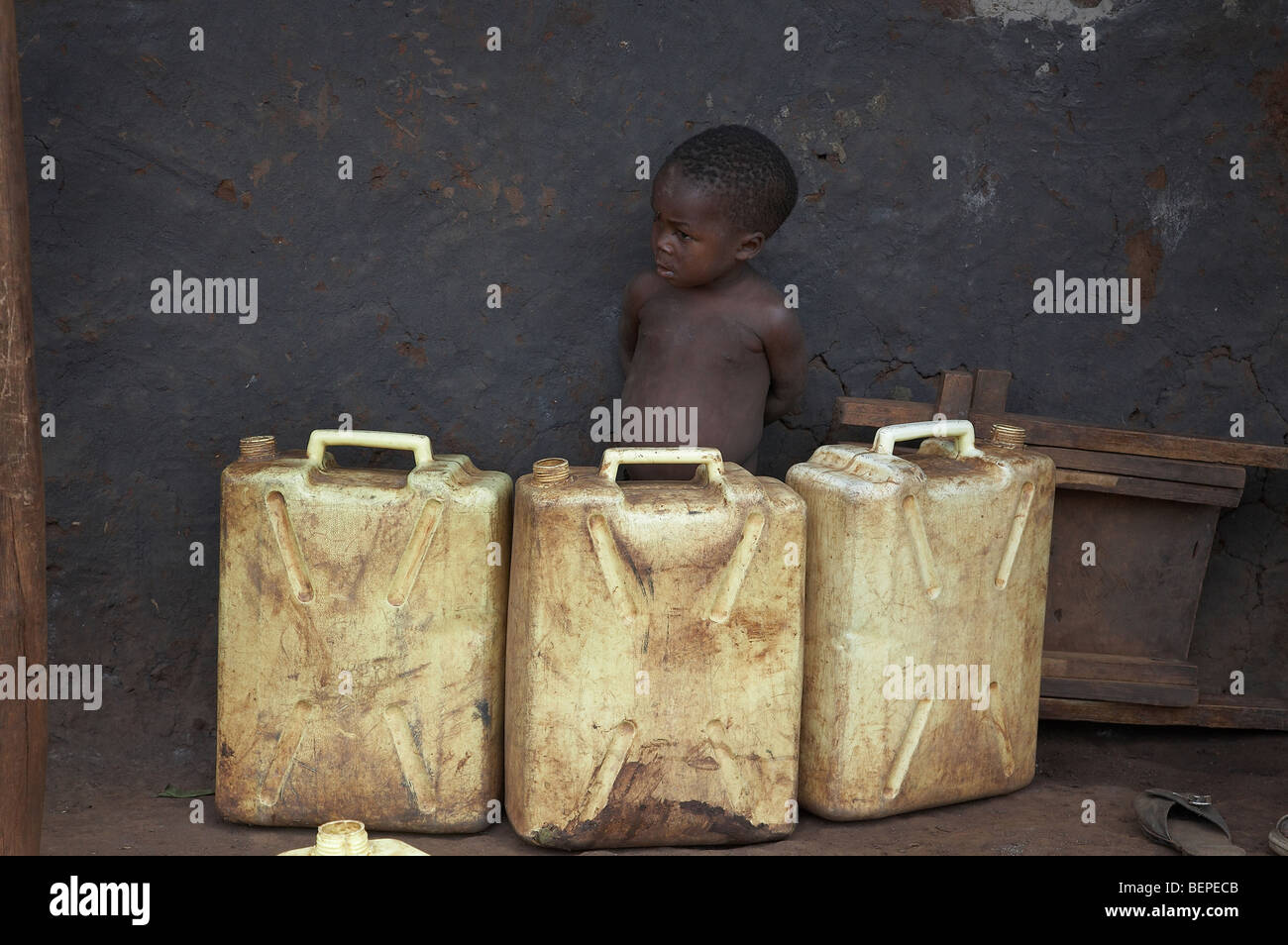 UGANDA Boy behind jerrycans (used for collecting water from public hand pump), Kayunga District. PHOTO by SEAN SPRAGUE Stock Photo