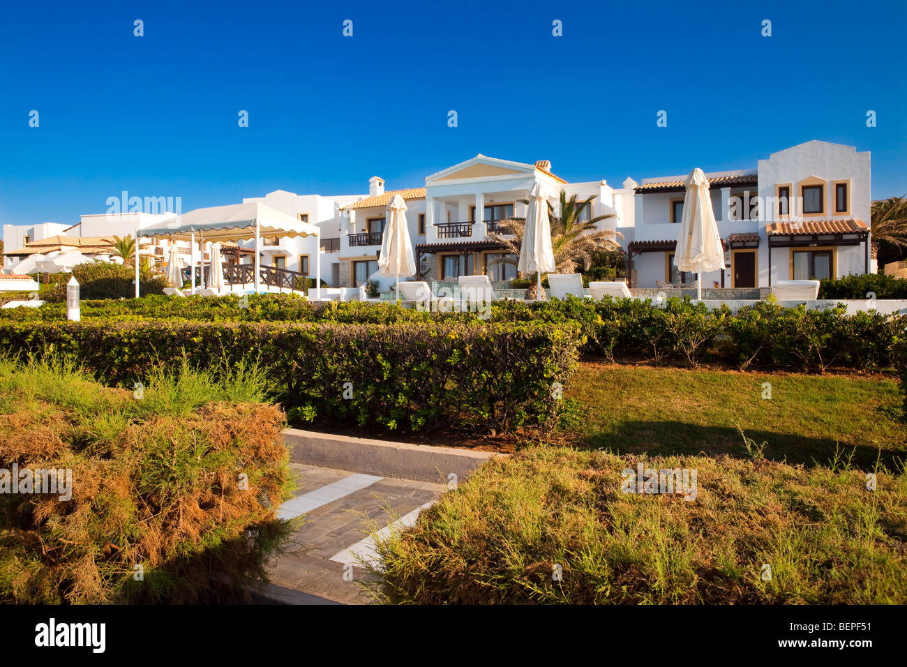 Territory of hotel with a path, palm trees and country houses Stock Photo