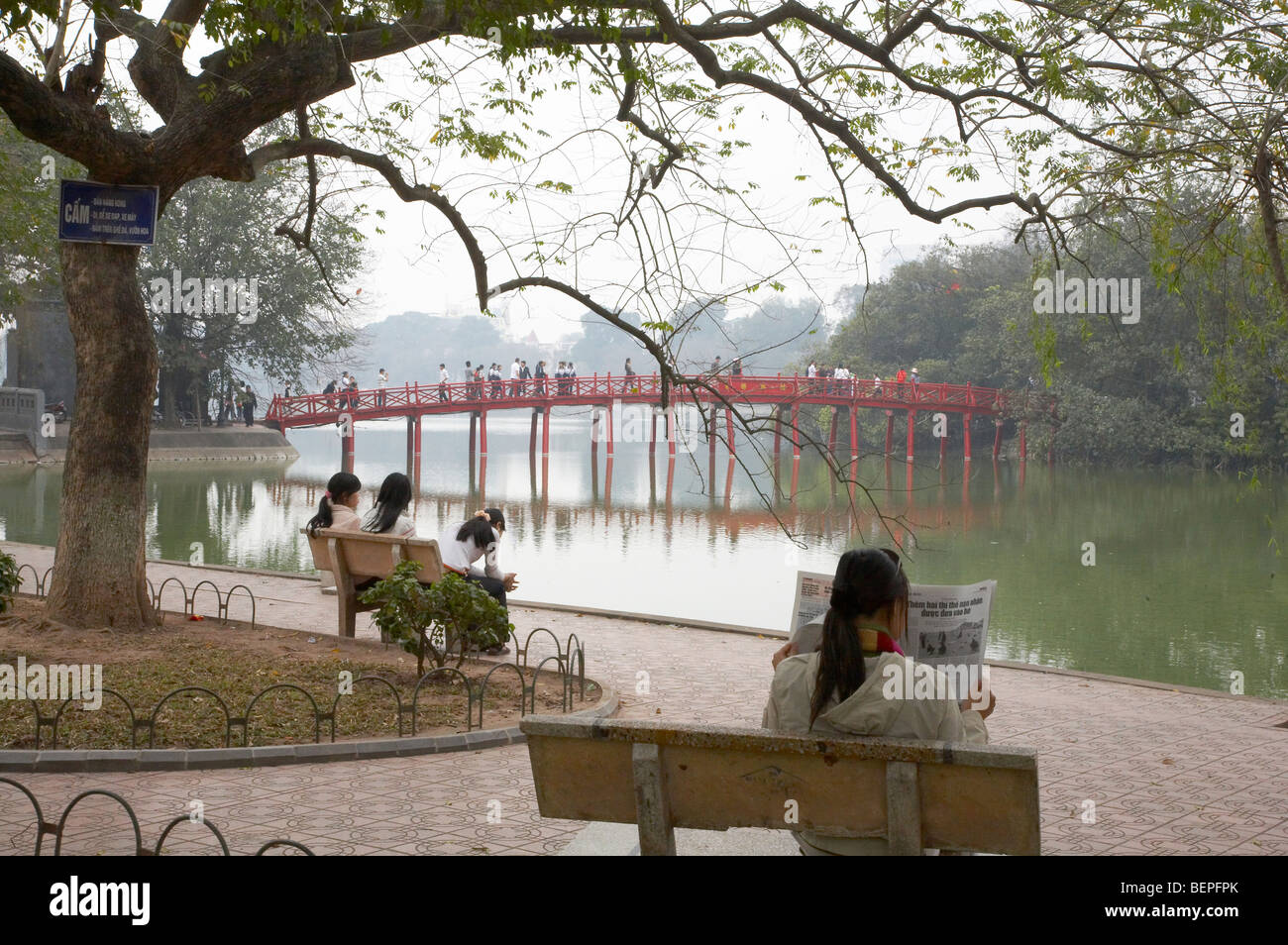 VIETNAM People relaxing besdie Hoan Kiem Lake, bridge to Ngoc Son temple in background, Hanoi. photograph by Sean Sprague 2008 Stock Photo