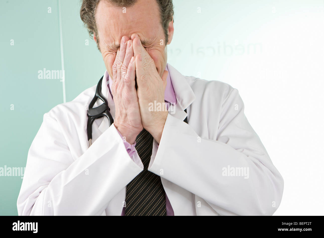 A doctor holding his hands over his face Stock Photo