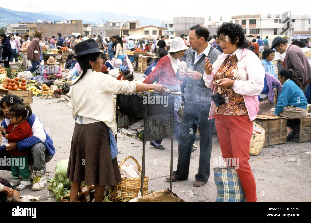 Woman roasting corn on small metal brazier in local upland Ecuador market. Stock Photo