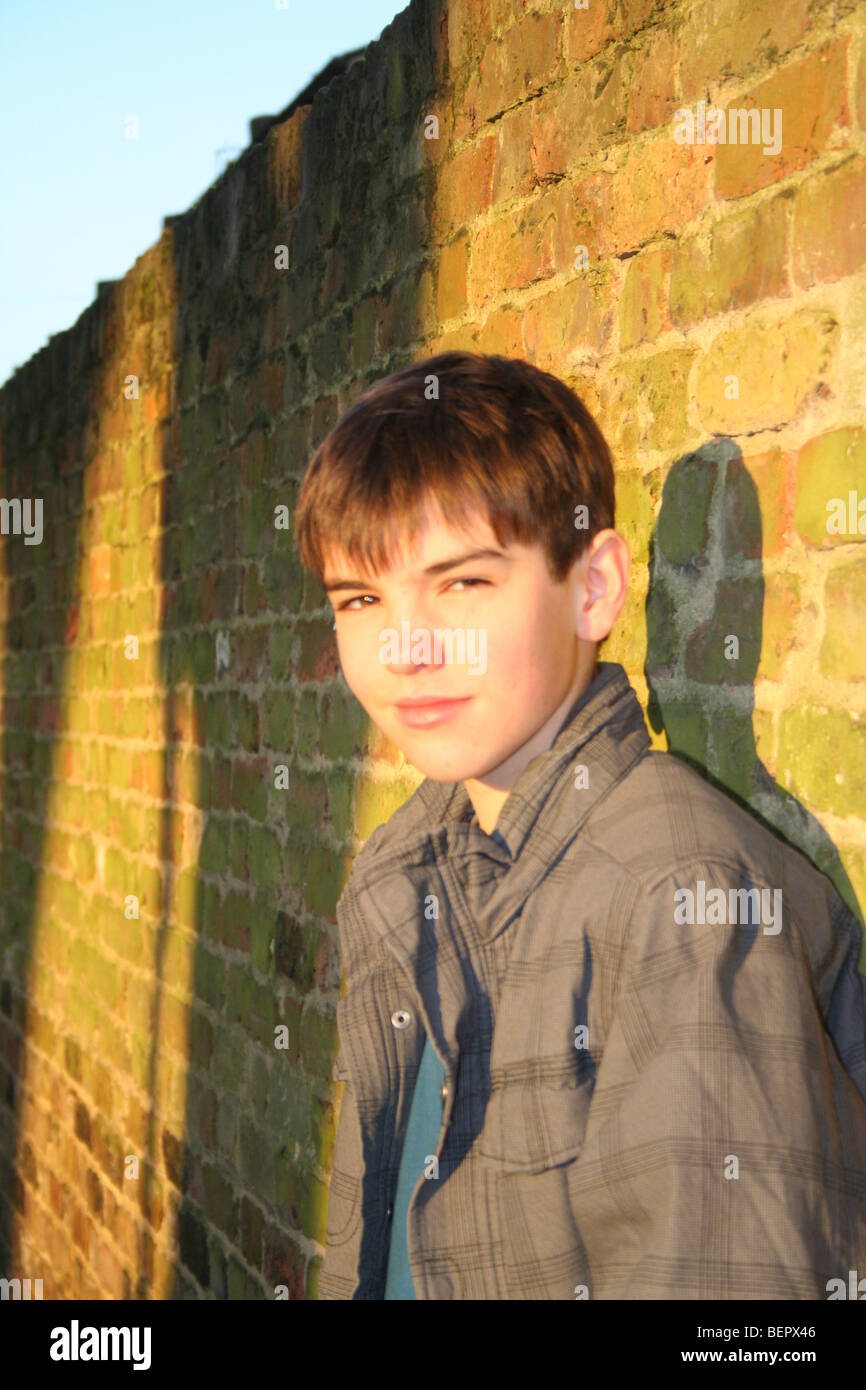 Young boy leaning against a brick wall Stock Photo - Alamy