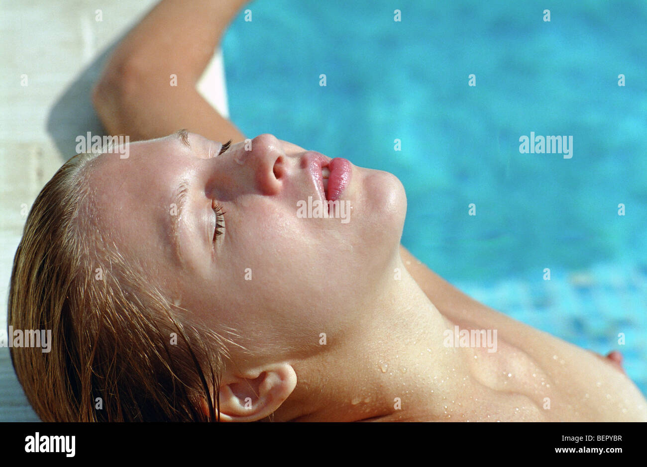 beautiful woman lying in water pool with closed eyes Stock Photo