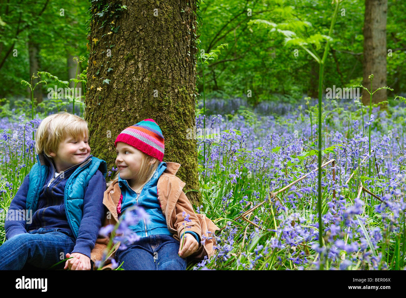 Boy and Girl sitting against a tree Stock Photo - Alamy