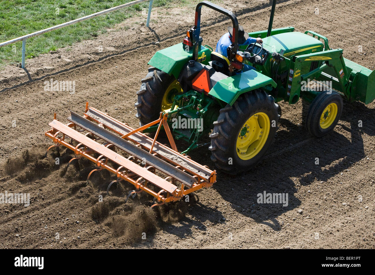tractor pulling rake on dirt track Stock Photo - Alamy