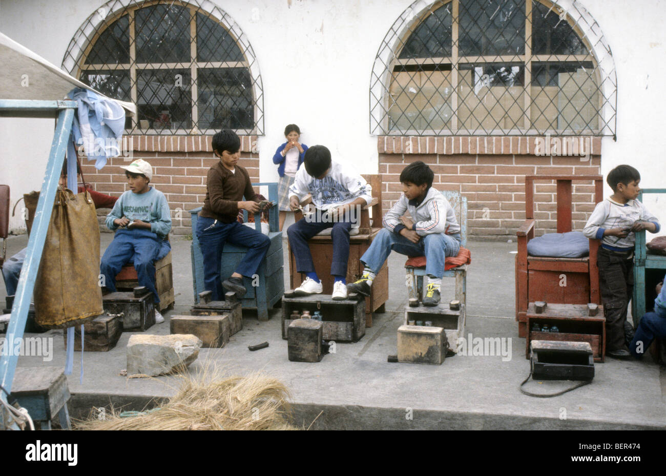 Line of young boys and shoe shine chairs waiting for customers Ecuador Market. Stock Photo