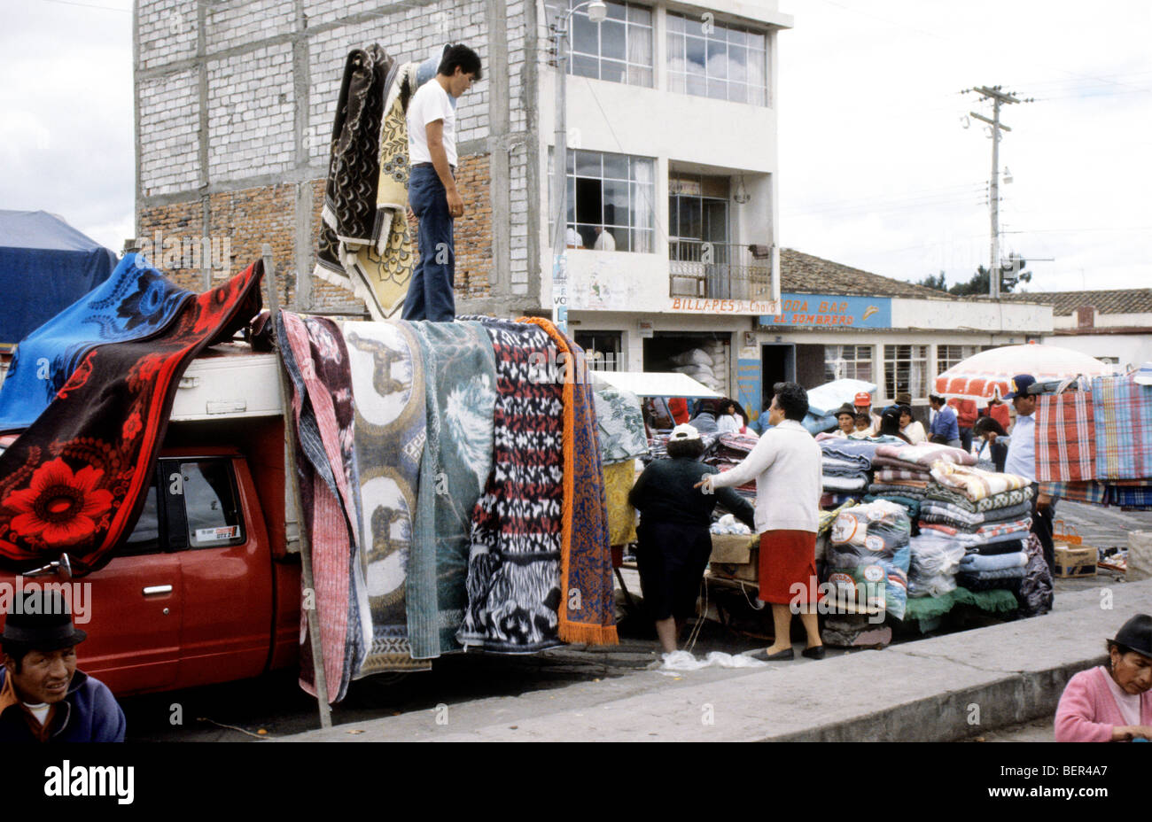 Truck draped in blankets and rugs with large pile of them stacked up behind he truck.  Ecuador highlands. Stock Photo