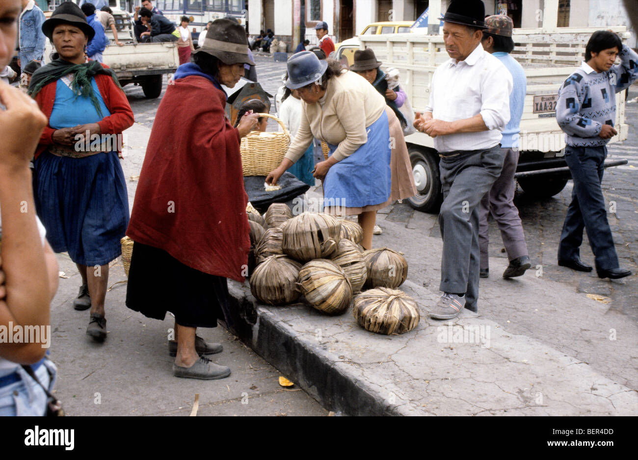 Sugar seller.  Large flattened soccer ball sized cakes of raw sugar wrapped in leaves.  Ecuador highlands local market. Stock Photo
