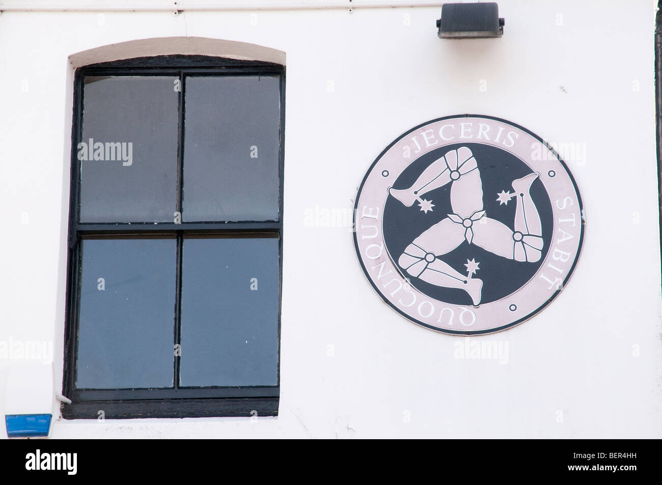 Isle of Man threelegged Triskelion logo on the side of a building next to a window Stock Photo