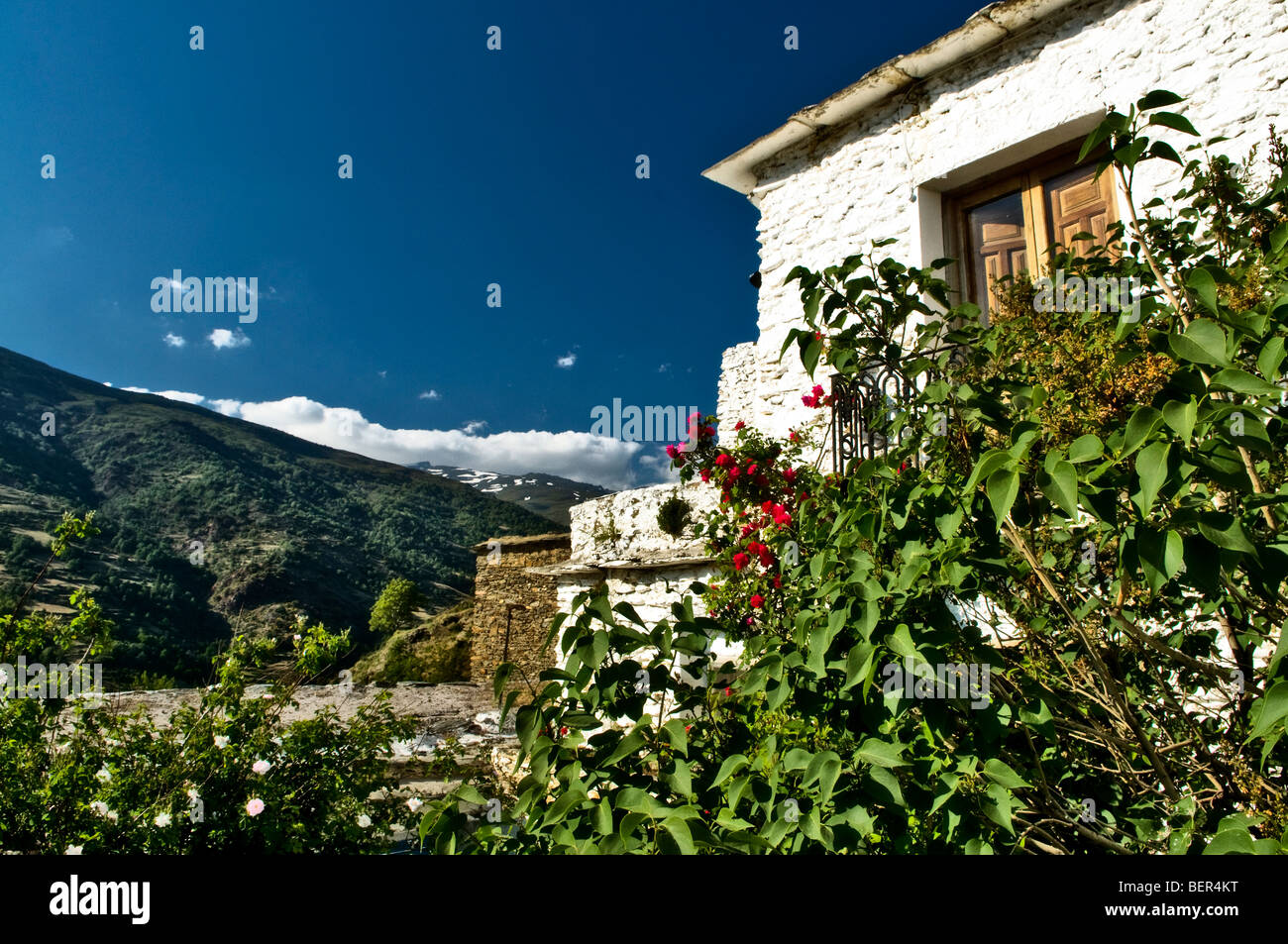 View past a white building of the pueblos blancos up to the snowy tops of Sierra Nevadan hills on a beautiful sunny day Stock Photo