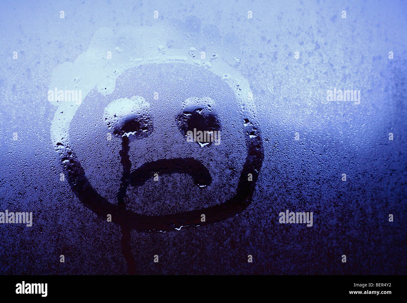 An unhappy childlike face drawn onto window condensation. Stock Photo