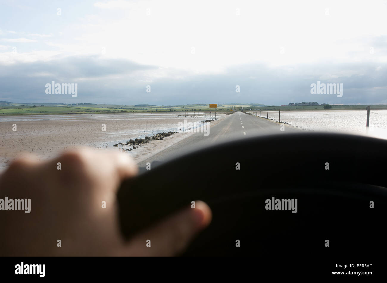 Driving on the causeway between the Holy Island of Lindisfarne and the mainland, Northumberland, UK. Stock Photo