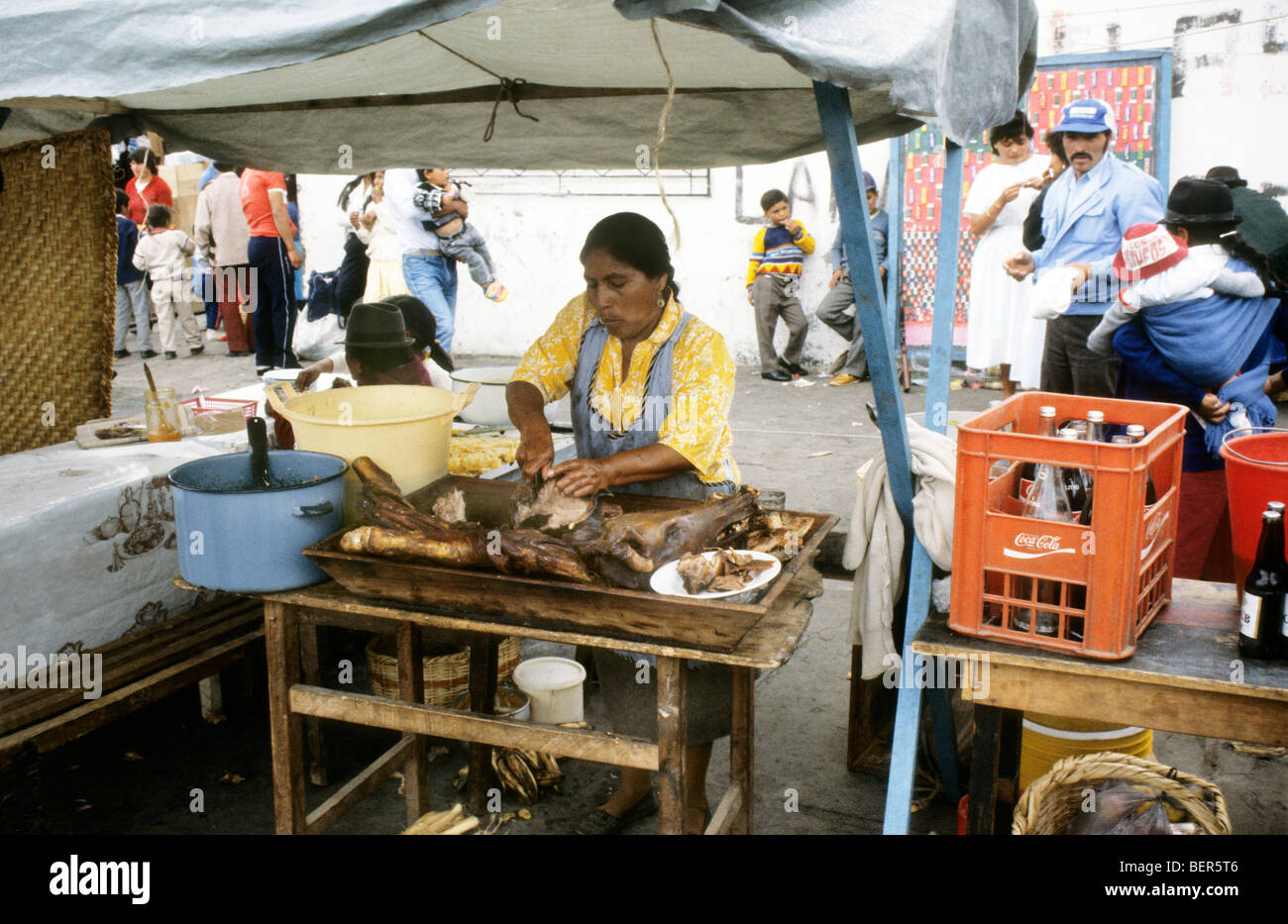Woman carving up portion of a whole roasted pig. Ecuador market.. Stock Photo