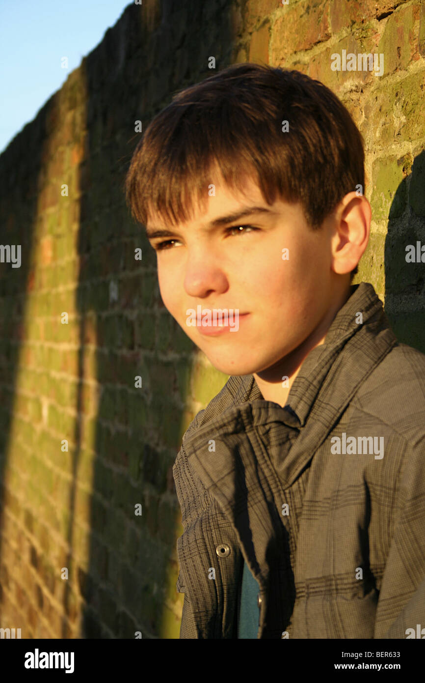 Young boy leaning against a brick wall Stock Photo