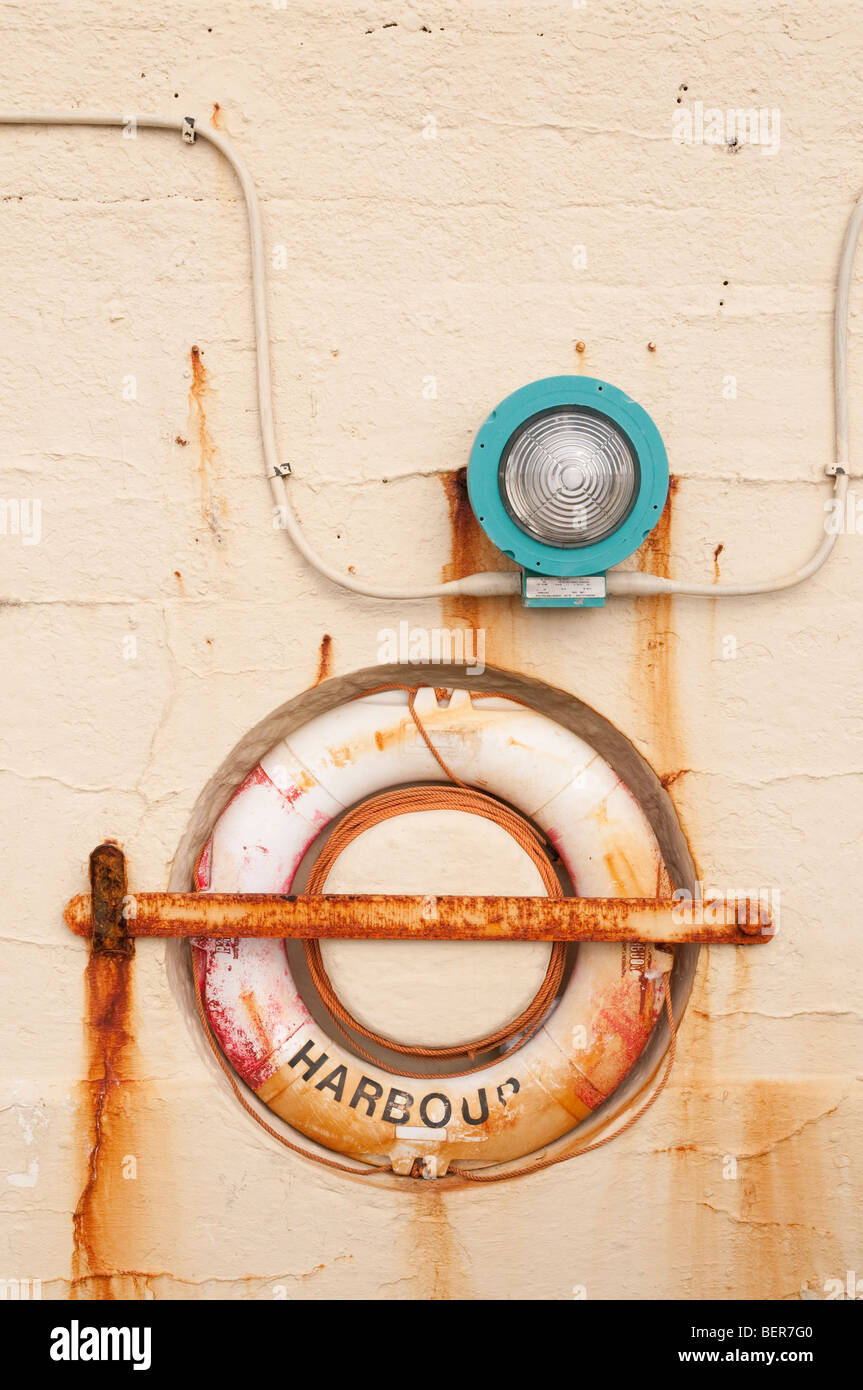 A light and rusty life belt mounted on a harbour wall in Peel, Isle of Man Stock Photo