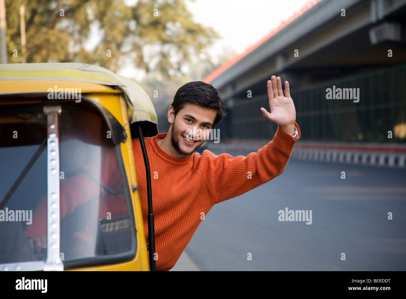 Man waving from an auto rickshaw Stock Photo