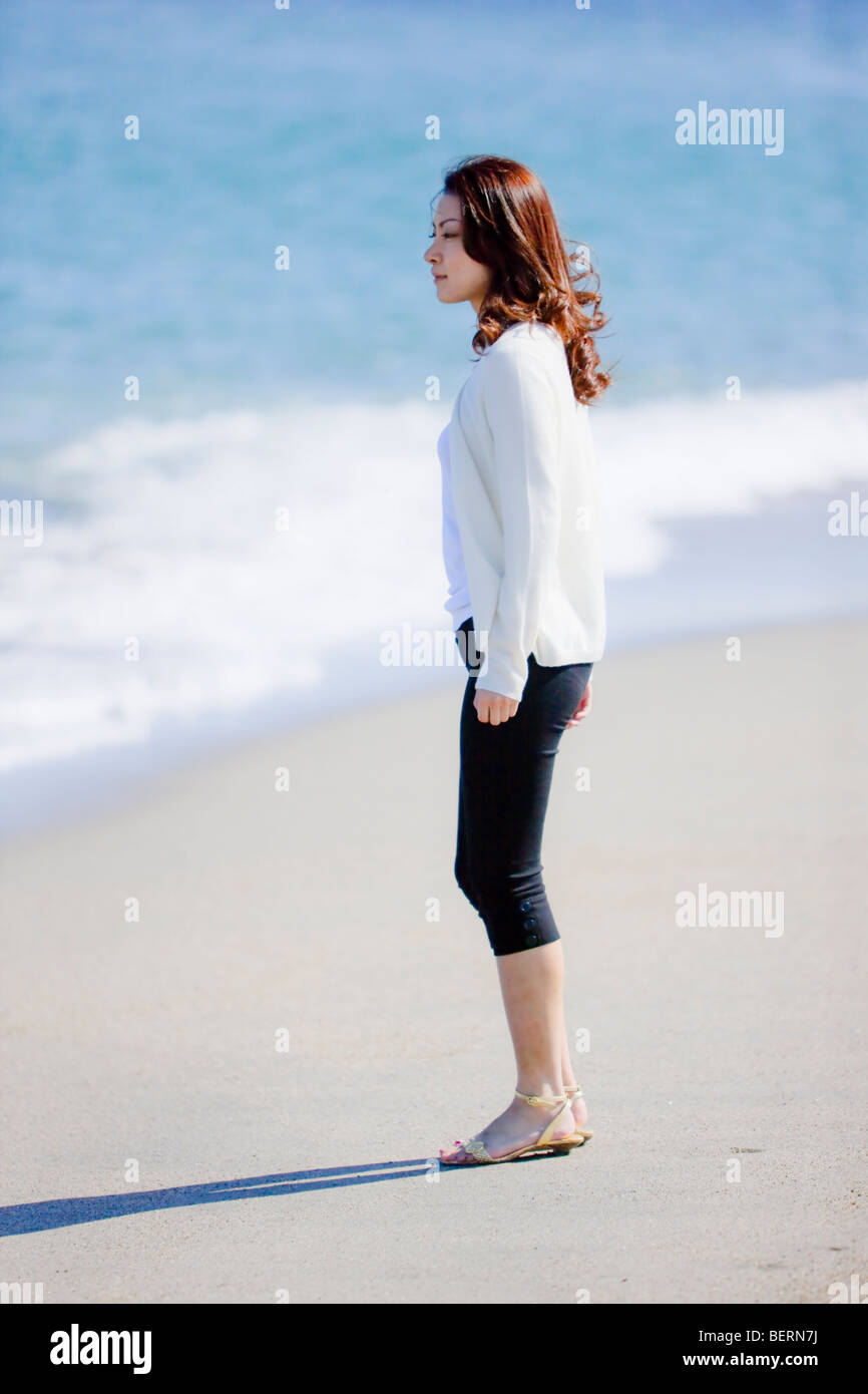 Young woman standing on beach Stock Photo - Alamy