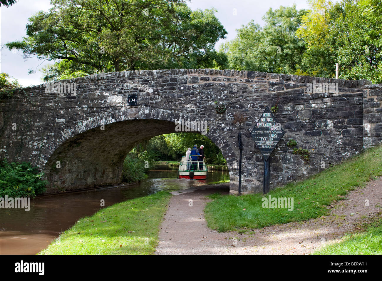 Canal boat saling under old stone bridge 134 on the Monmouth and Brecon Canal taken at Llangynidr mid Wales on fine day Stock Photo