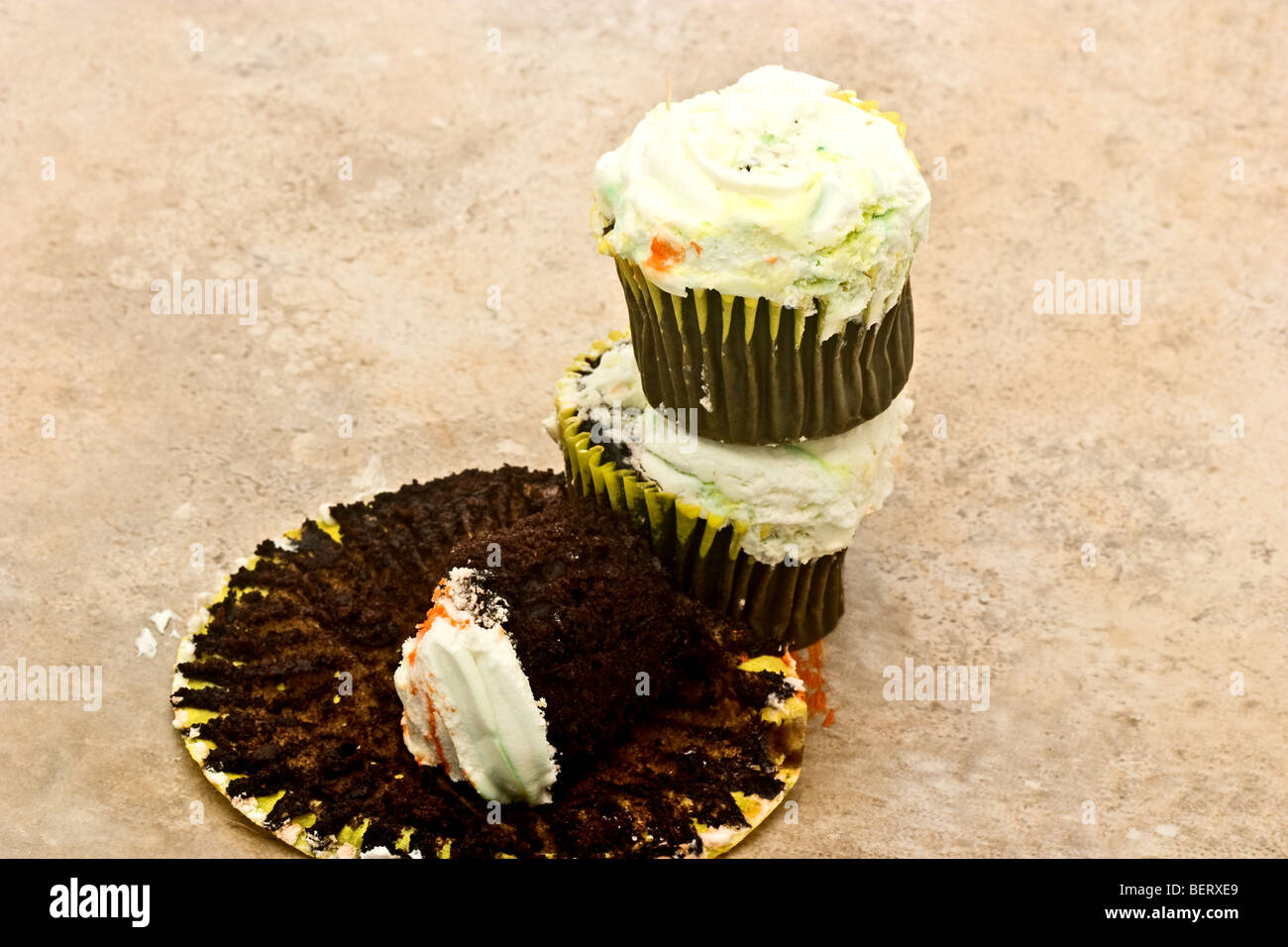Pile of two chocolate cupcakes, with a third almost eaten Stock Photo