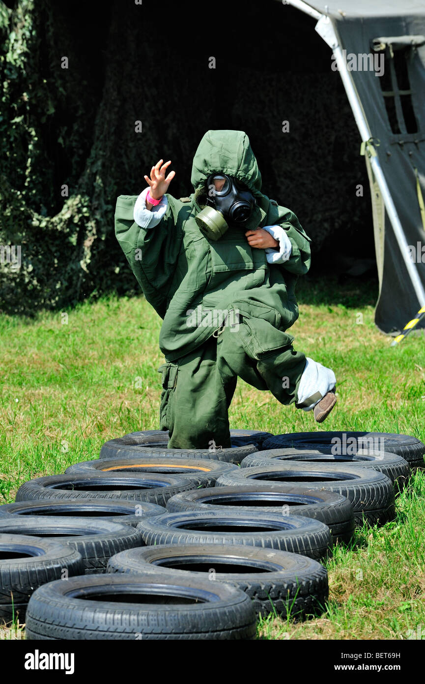 Obstacle course for children equipped with gas mask and chemical warfare protection clothing at airshow, Koksijde, Belgium Stock Photo