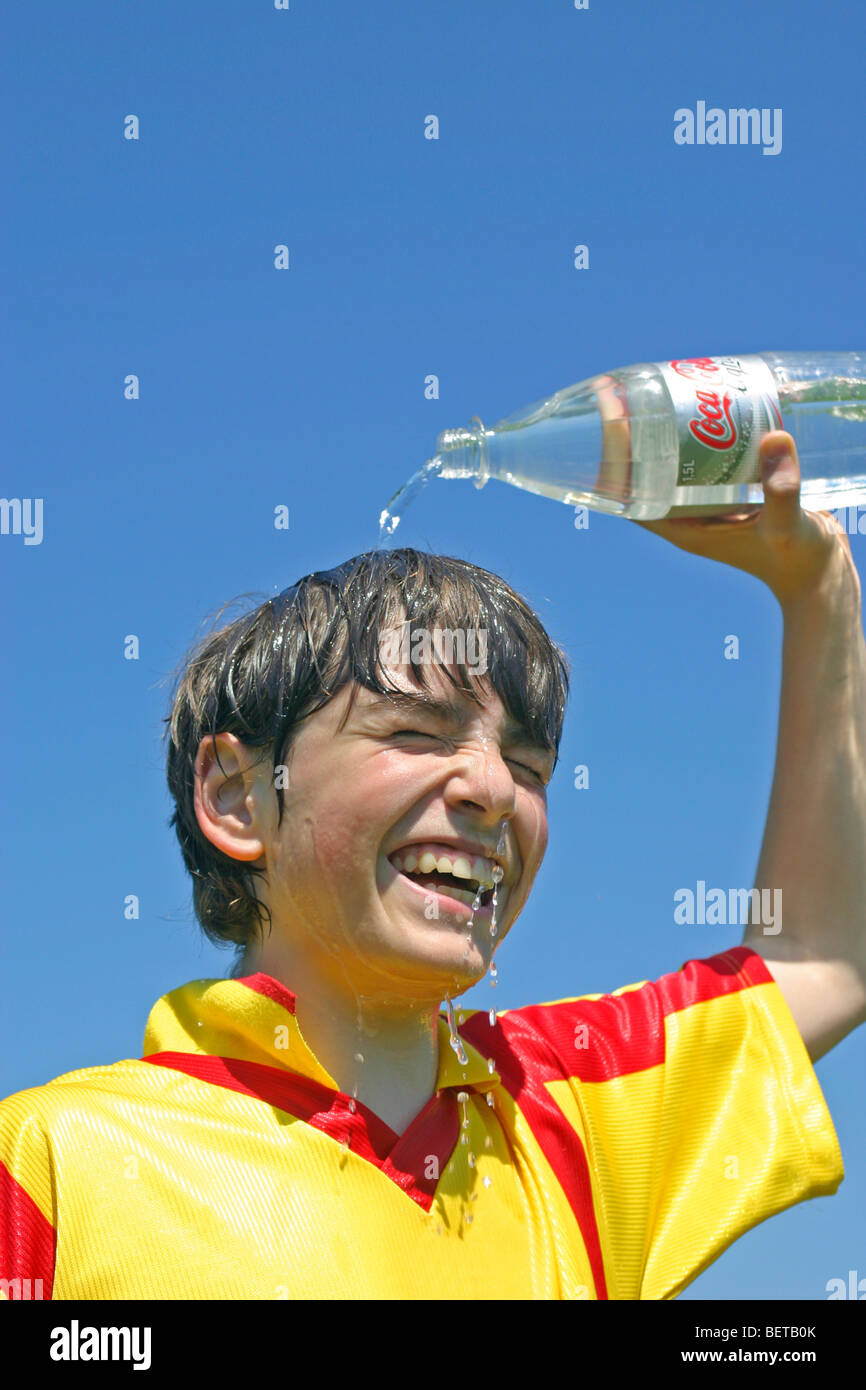 young boy pouring water over his head after playing football Stock Photo