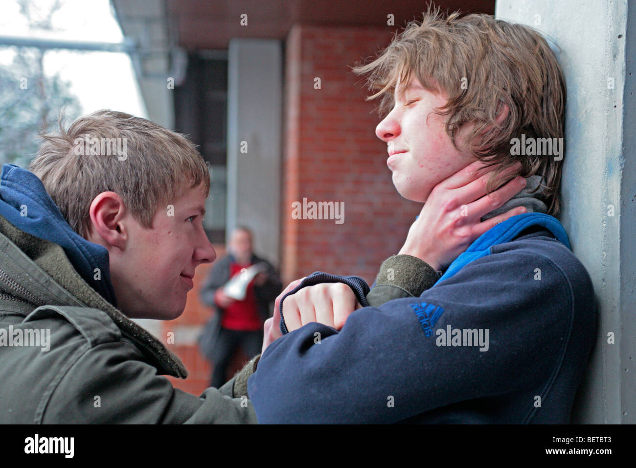 two boys fighting while a teacher is reading his paper Stock Photo