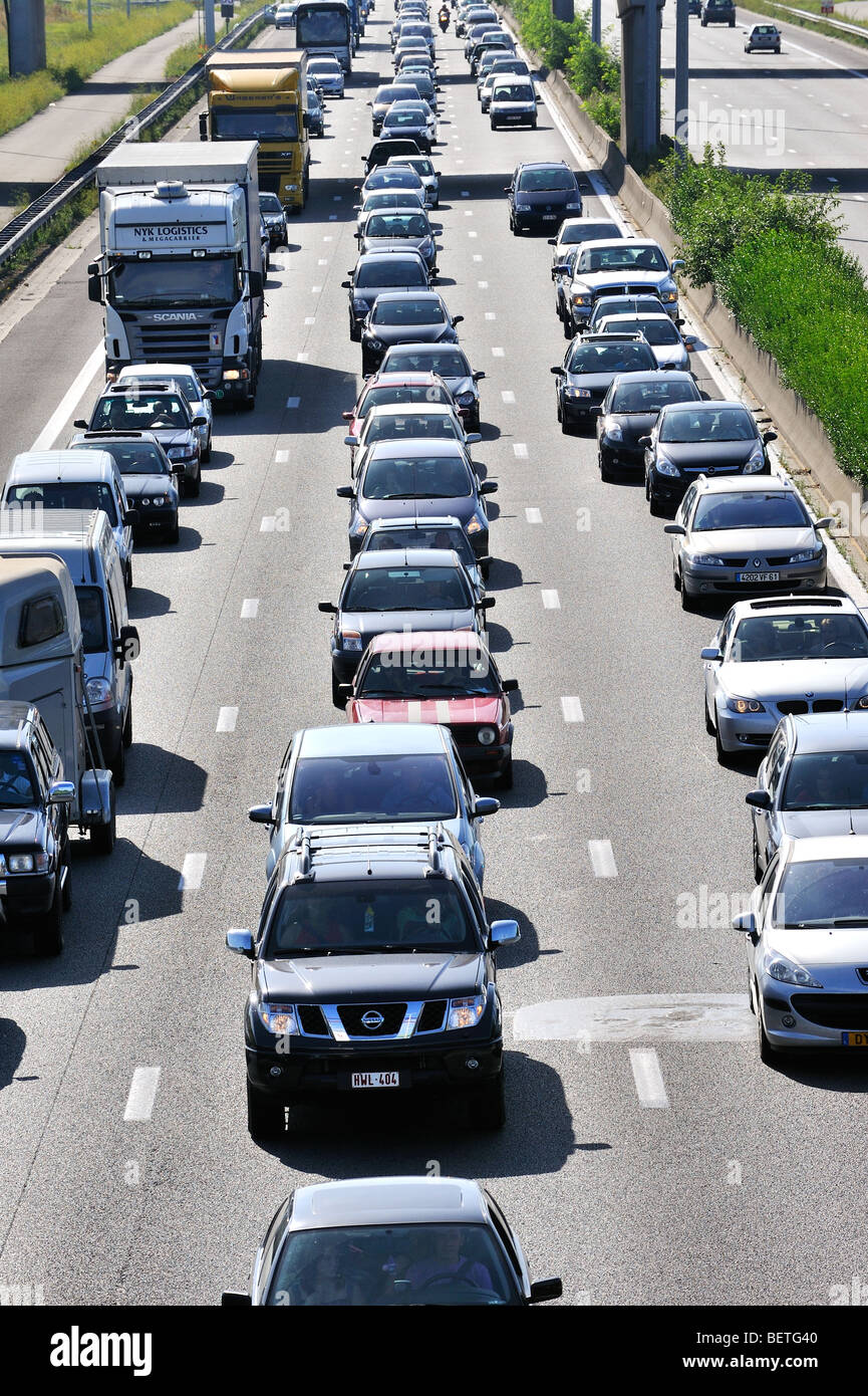 Cars and trucks queueing in highway lanes during traffic jam on motorway during summer holidays, Belgium Stock Photo