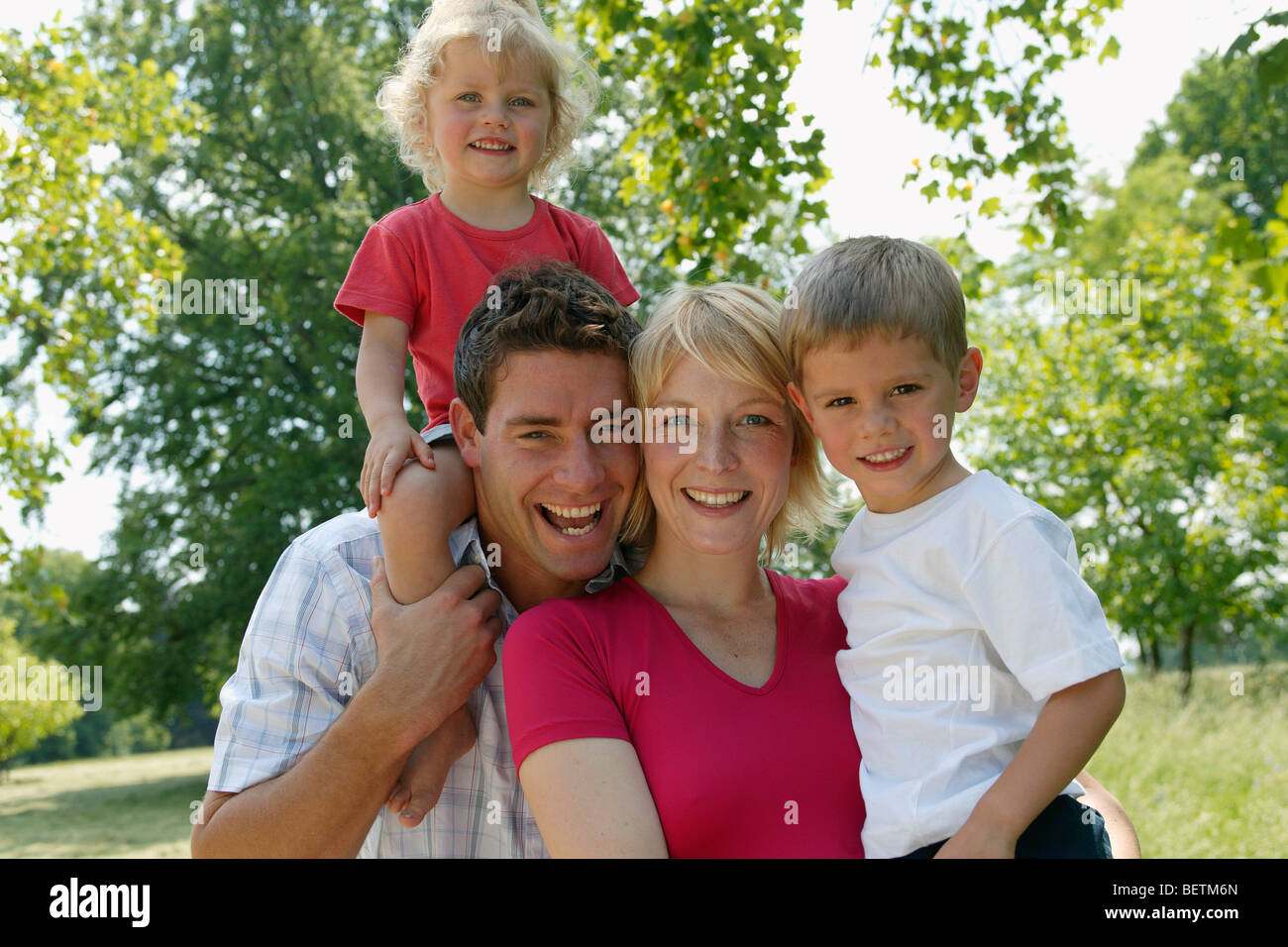 family of four in the park smiling at the camera Stock Photo - Alamy
