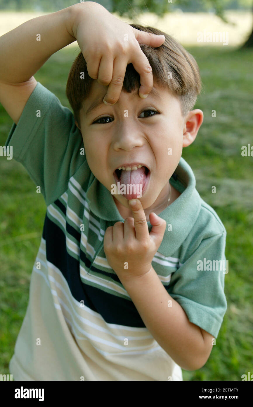 young boy outdoors, pulling a silly face, sticking his tongue out Stock Photo