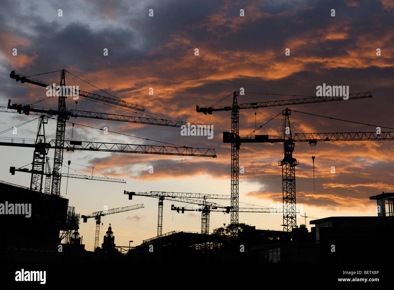Tower construction cranes silhouetted against red sunset Stock Photo