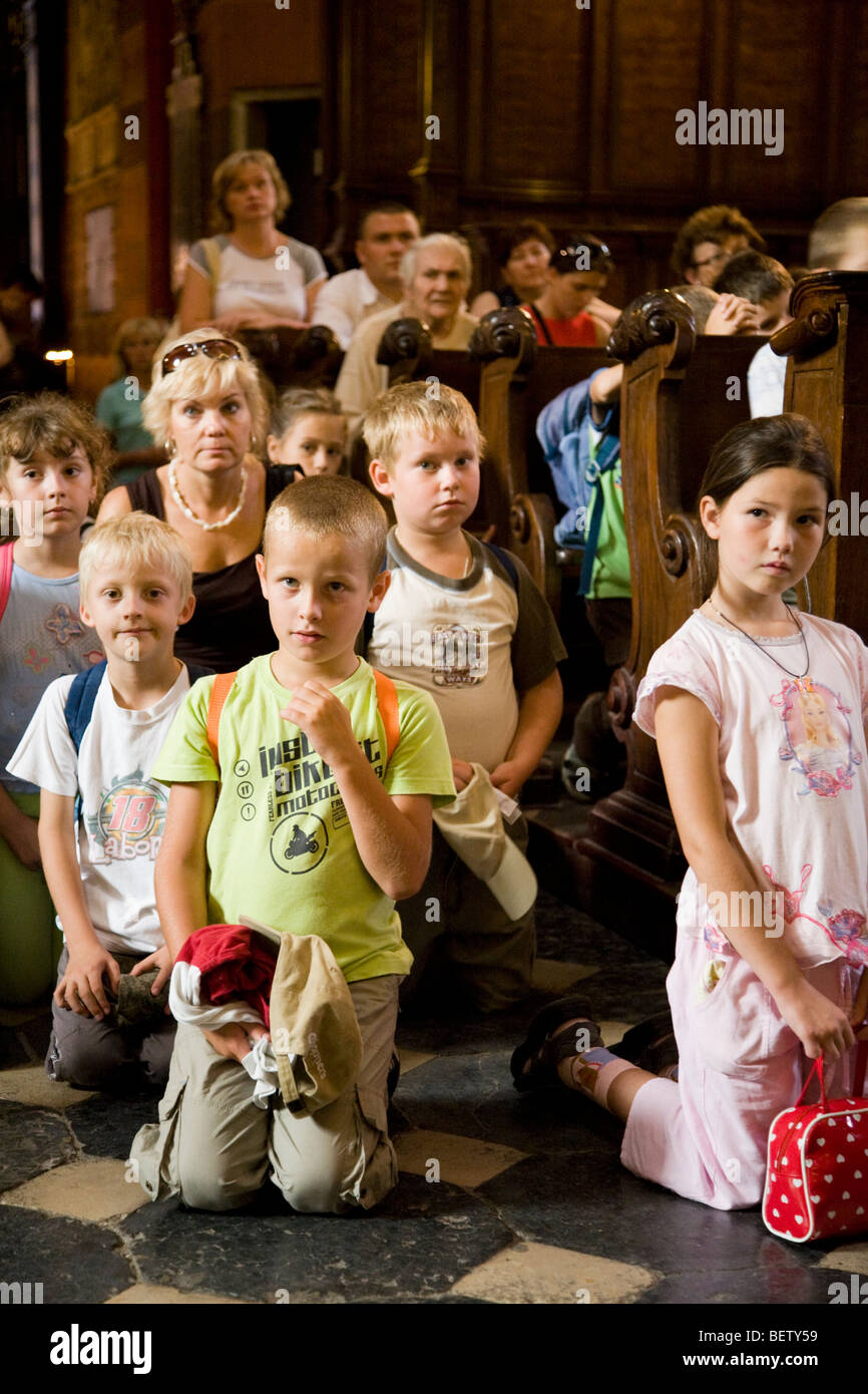 Polish children in a school party pray in the church nave of St Marys Basilica. Krakow. Poland. Stock Photo