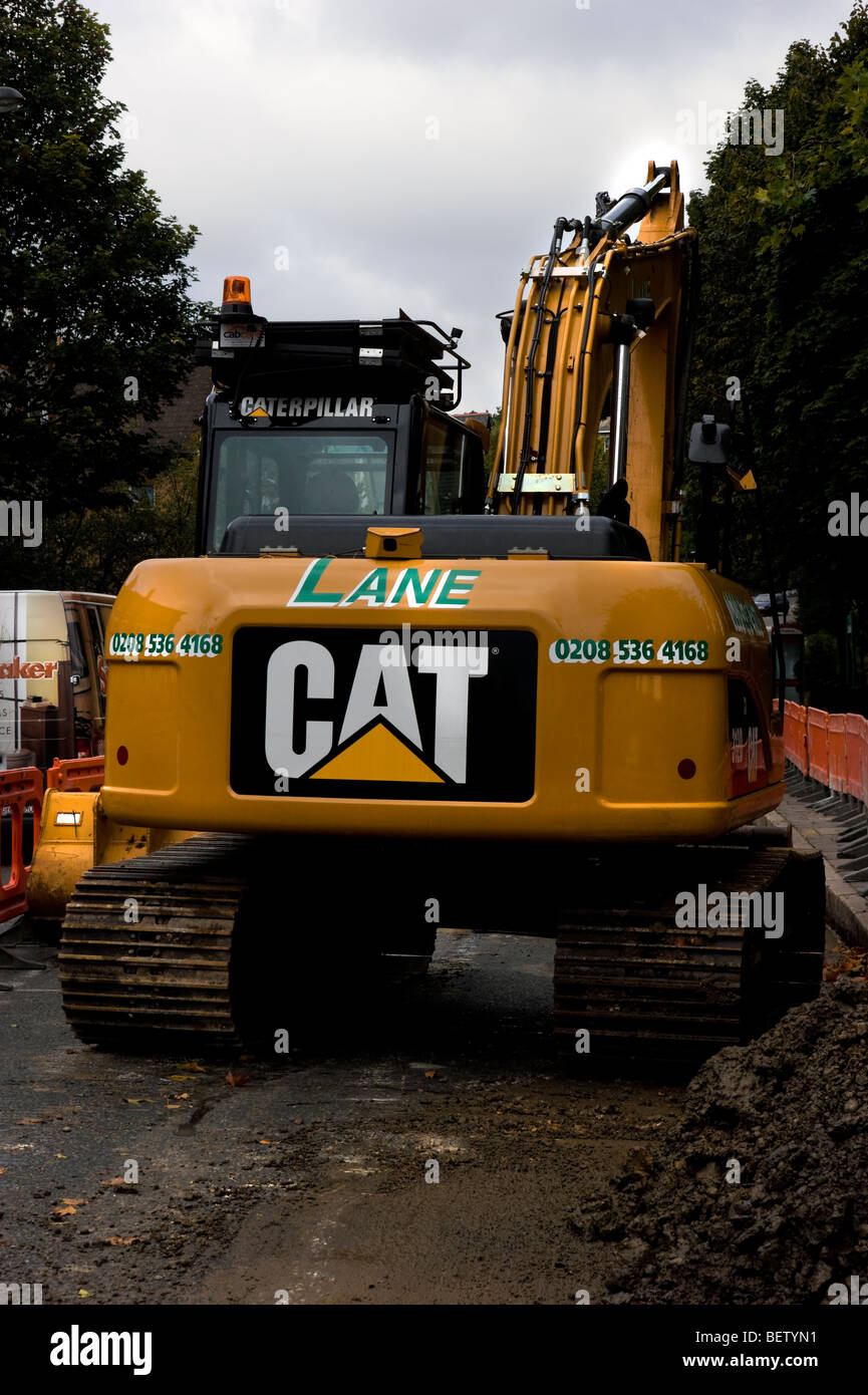 Caterpillar  digger in Crouch hill , North London seen in use resurfacing the road at the  bus stop area. Stock Photo