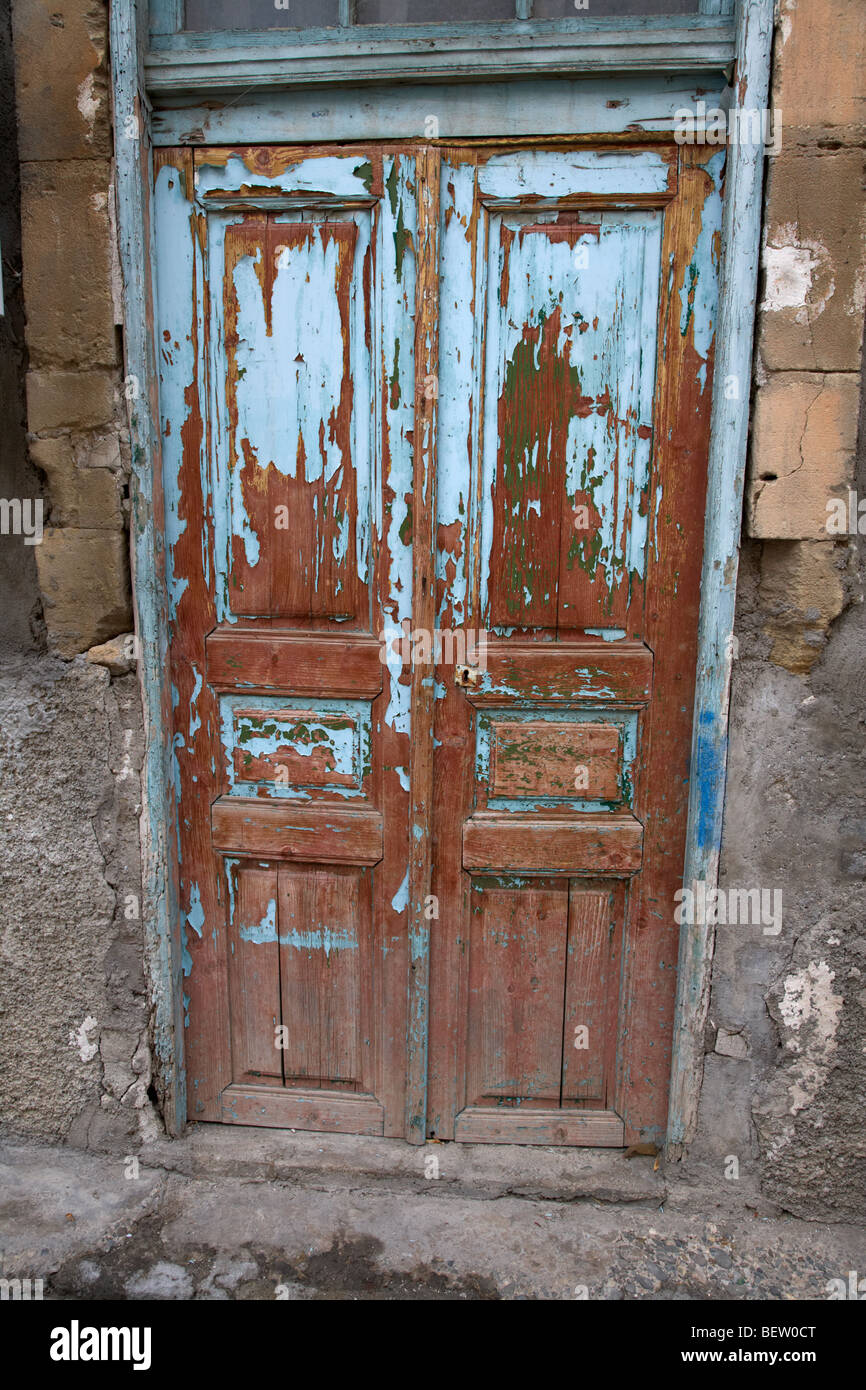 flaking painted wooden door with numerous layers of old paint in a