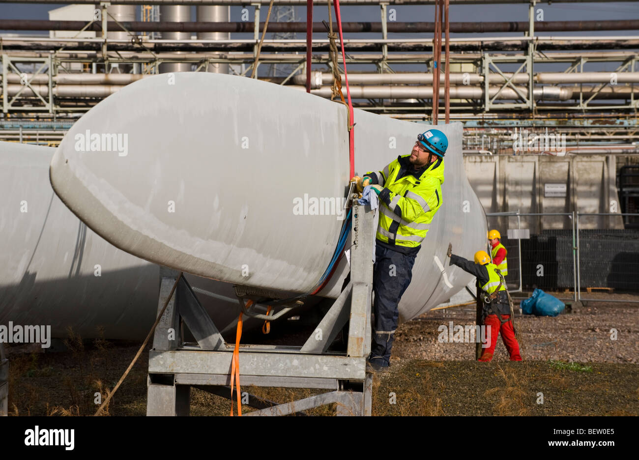 Riggers preparing for crane lift of blades to be fitted to Nordex N90 wind turbine under construction at UK Stock Photo
