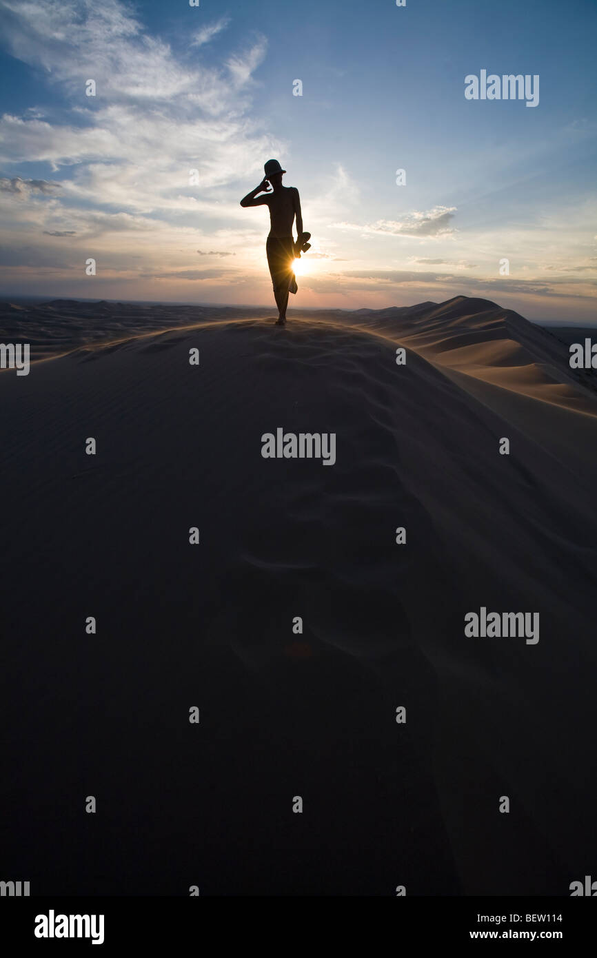 Silhouette of man on top of the dunes in the Gobi desert at sunset Stock Photo
