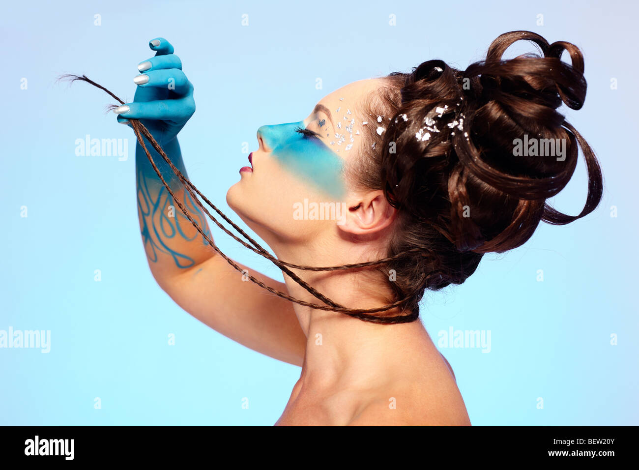 portrait of beautiful girl with blue stripe facial bodyart and fantasy hair-do pilling her several thin long braids Stock Photo