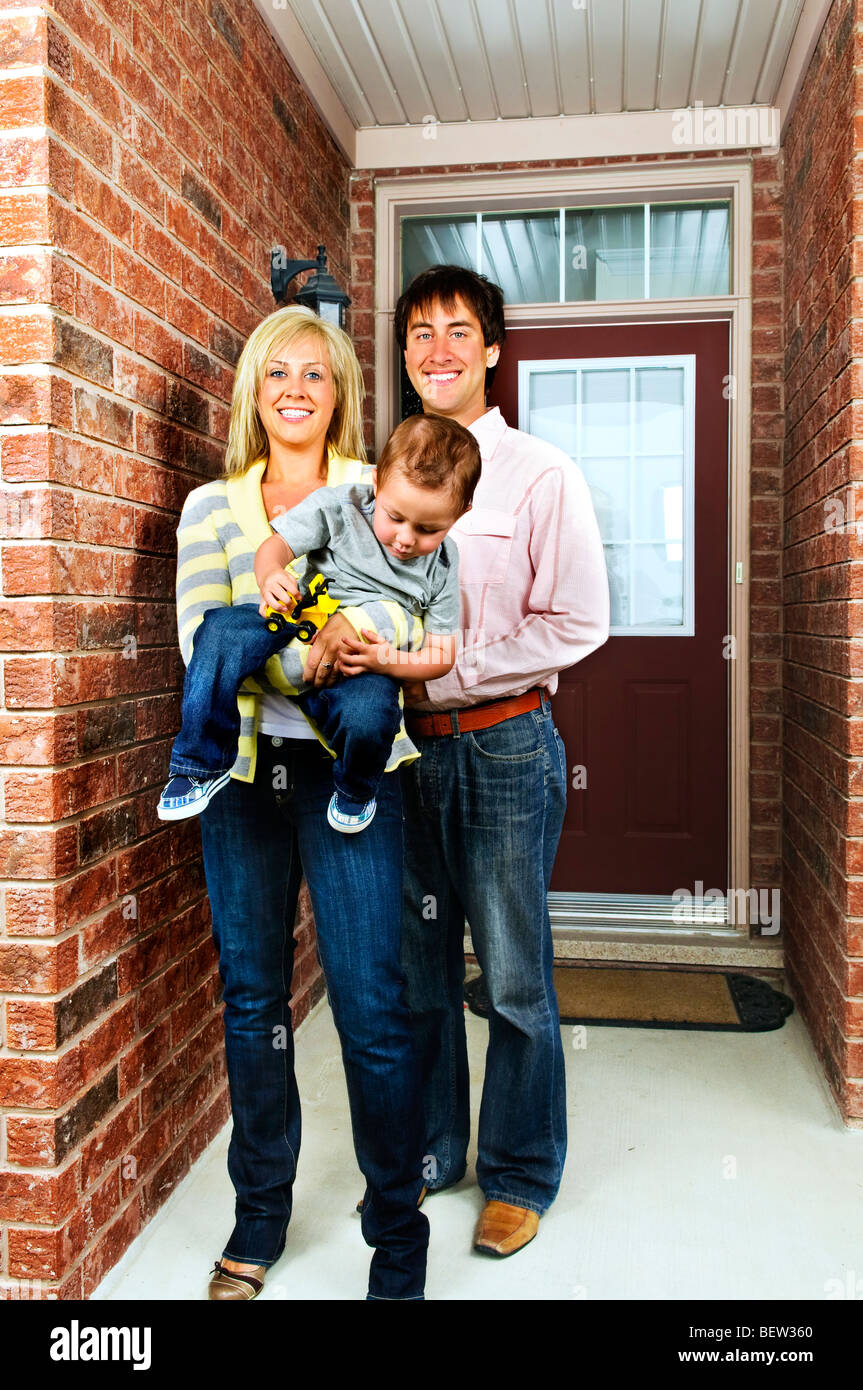Young happy family in front of house Stock Photo - Alamy