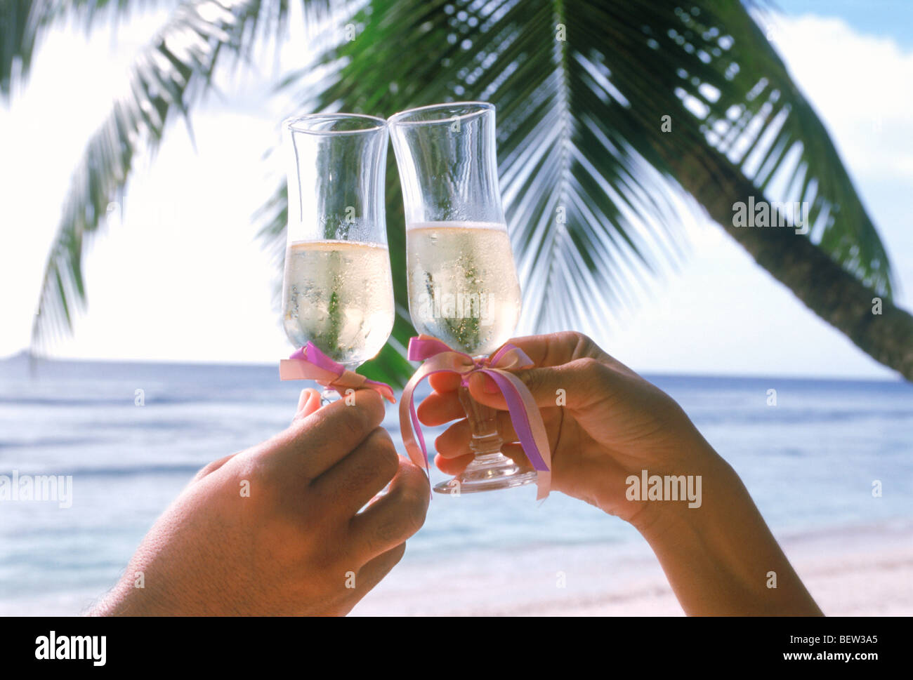 Two people toasting a lovely island holiday with glasses of champagne Stock Photo