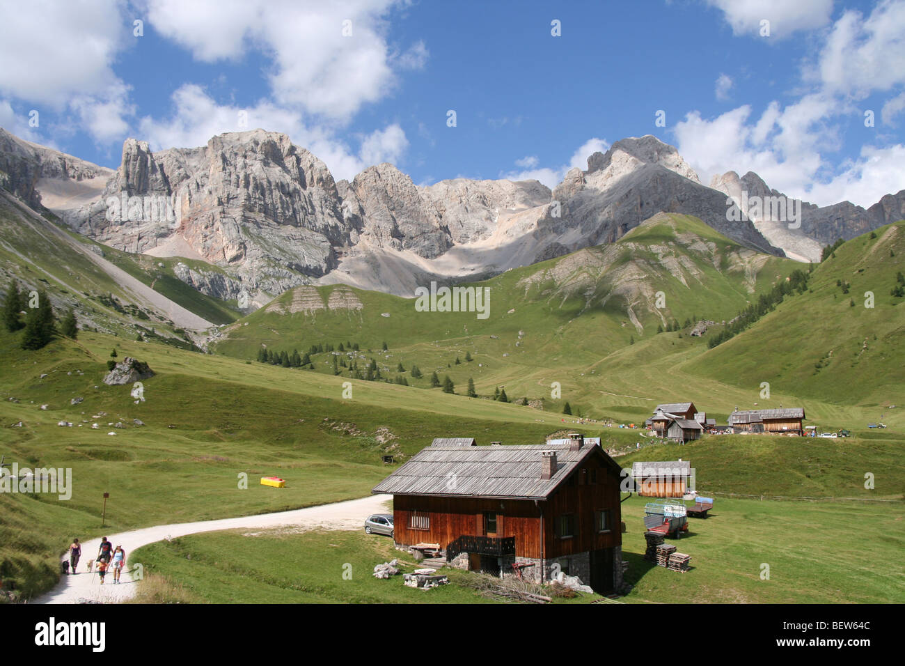 family strolling on lane near timber chalets for haymaking in the Italian Dolomites summer Stock Photo
