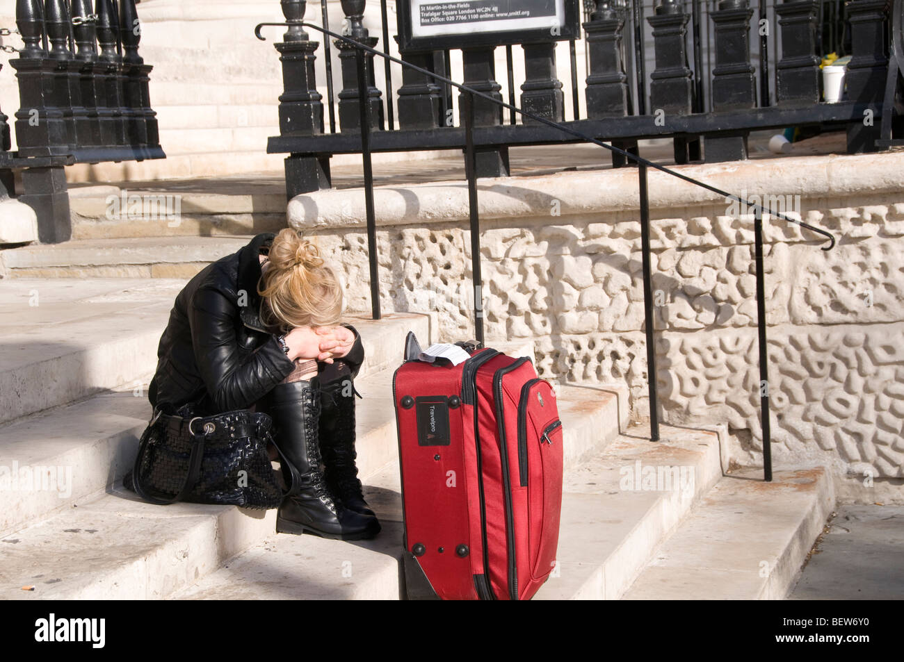 St Martins-in-the-Fields, Trafalgar Square. Despairing young woman sitting on steps with her head on her knees.. Stock Photo