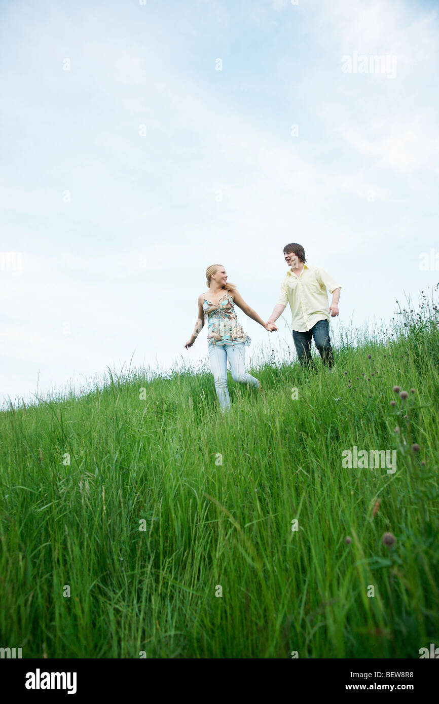 A young couple walking through a meadow, low angle view Stock Photo