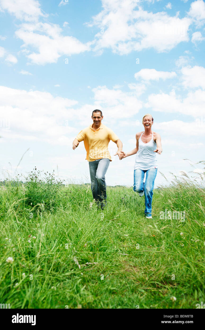 Couple running over a meadow, low angle view, front view Stock Photo