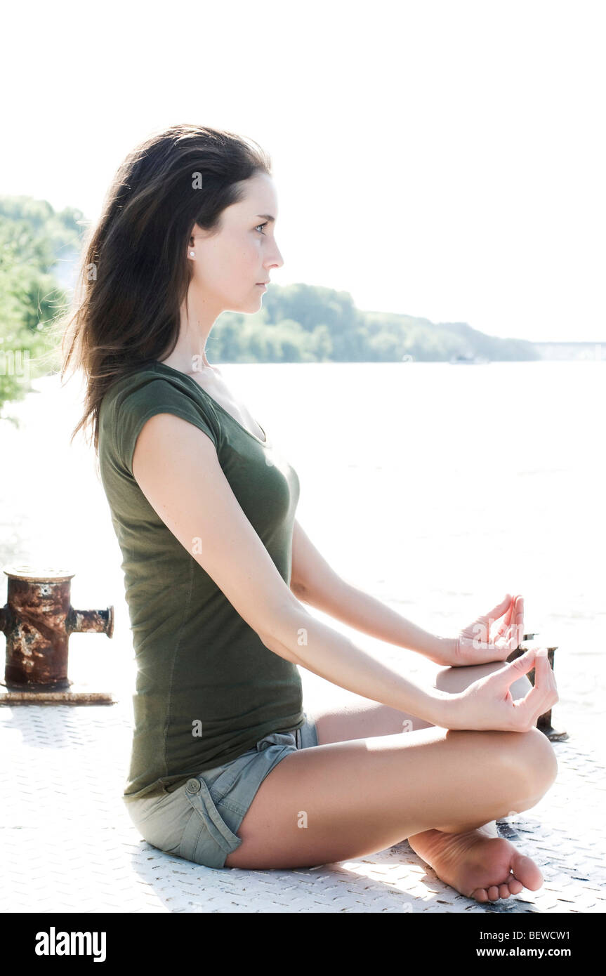 Young Woman Sitting Cross Legged At A Shore Side View Stock Photo Alamy