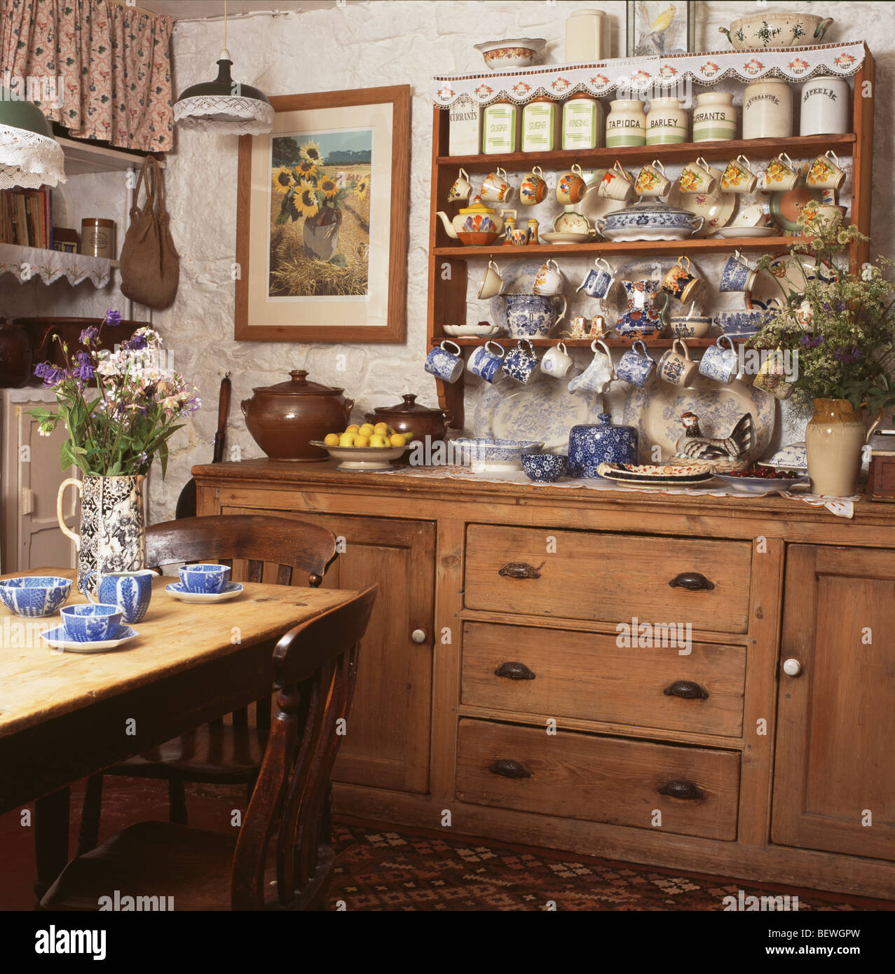 Collection Of China On Cluttered Shelves Above Pine Dresser In
