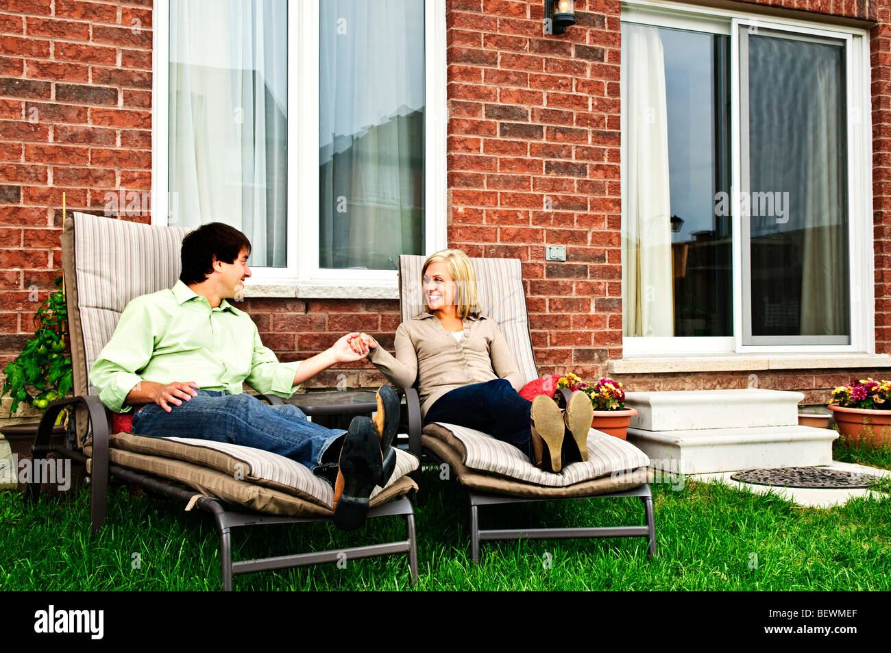 Happy couple in backyard of new home sitting on lounge chairs Stock ...