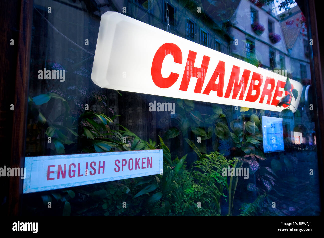 Illuminated red 'Chambres' sign in french B+B window with English spoken label Stock Photo