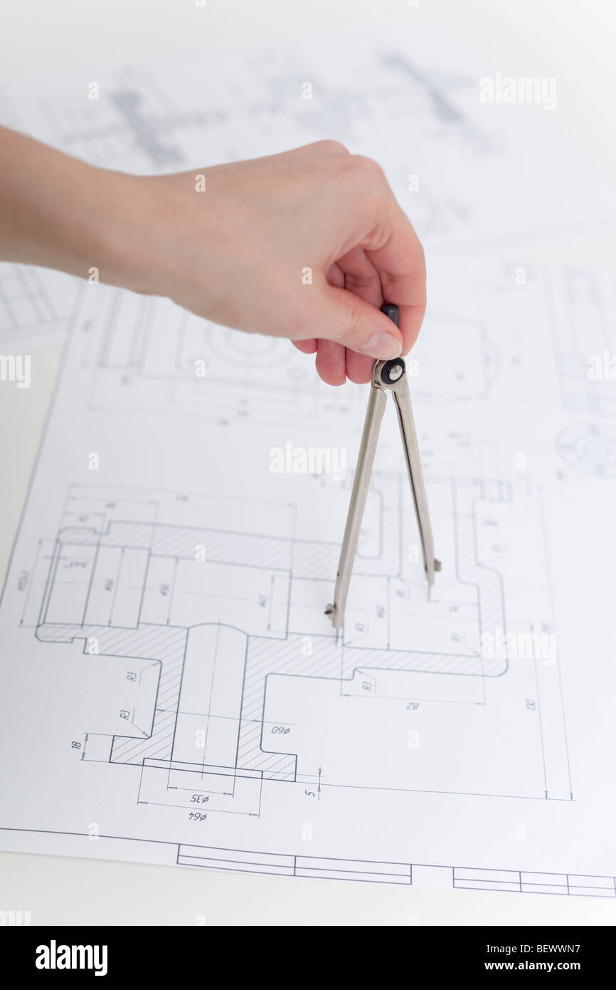 The hand holds metal compasses against drawings Stock Photo - Alamy