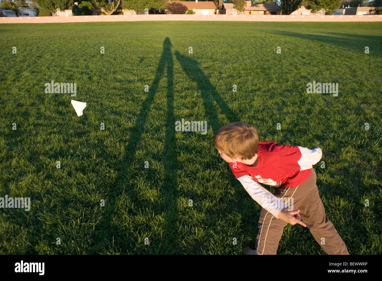 a boy throws a paper airplane into the air at a park, sunset Stock ...