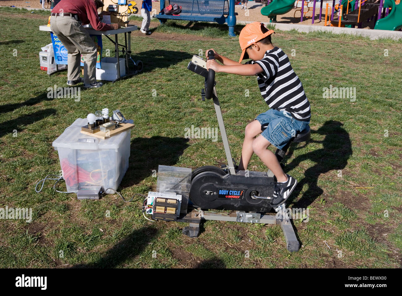 boys creating energy by pushing bike pedals, lighting up bulbs Stock